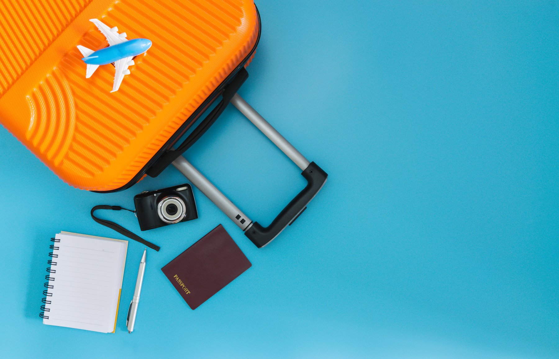 Flat lay orange suitcase with traveler accessories on soft blue background. travel, summer and holiday concept